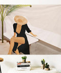 Artistic wall decor featuring a woman in a black dress and a hat, seated beside a plant and minimalist furniture.