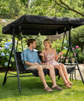 Couple sitting on Three Seat Outdoor Porch Swing With Adjustable Canopy in a garden setting