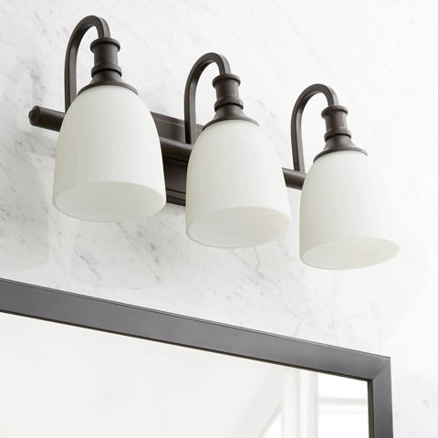 Three Light Bathroom Vanity Light In Oiled Bronze With Clear Seeded Glass From The Richmond Collection Modern Transitional Style LED Compatible And Damp Rated For Bathrooms Perfect For Contemporary Master Bath Or Powder Room. Oiled bronze finish above bathroom mirror with three lights.