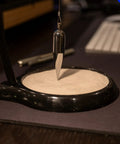 Dope Pendulum Demonstration Kit Reveals Earth's Rotation With Every Swing; black pendulum creating sand patterns on desk