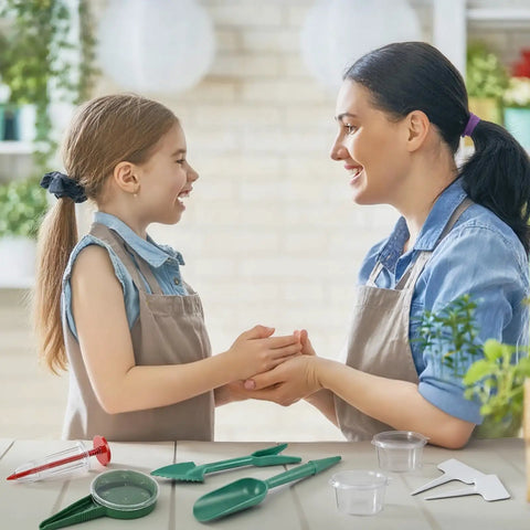 Mother and daughter smiling with Seven Piece Mini Seed Spreader Set, seed sowers, dibber, widger, and storage boxes on table
