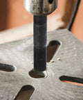 Close-up of Heavy Duty Hydraulic Punch Driver Kit with pull rod lock cap creating hole in metal sheet for electrical work.