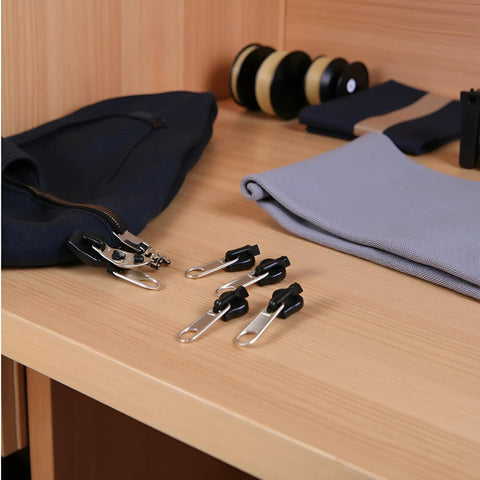 Six Piece Universal Zipper Repair Kit With Instant Fix Sliders And Teeth To Fit Most Zippers On Clothes Luggage And Backpacks Easy Do It Yourself Fix No Sewing Required displayed on a wooden surface next to fabric and zippers