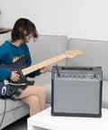 Person playing guitar next to 40 Watt Portable Electric Guitar Amplifier With 8 Inch Speaker And Headphone Jack Aux Input on table