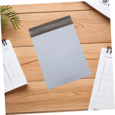 Waterproof Poly Mailer Bags 10x14 Inches White Self Seal Envelopes on a wooden table with calendars nearby