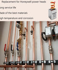 Copper plumbing manifold with vertical pipes, red and blue valve handles, and electrical control boxes.