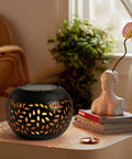Outdoor Solar Lanterns Waterproof For Porch Garden Patio Vintage Leaf Pattern Metal Lanterns With Warm Flame Light Great Gift For Women Moms Grandmas Perfect For Weddings Yards Camping And More Black on a table next to a sculpture and plant.