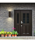 Aluminum Outdoor Up And Down Wall Lantern Light in Antique Bronze by door, 6 inch square sconce illuminating entrance.