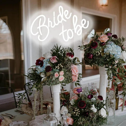Bride To Be Neon LED Sign White Letters Light For Bridal Shower And Bachelorette Party Wall Decor Reusable Neon Wall Art Gift For Engagement Celebrations Party Ready 17.7 x 12.2 Cm above floral arrangement at bridal event