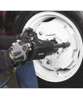 Heavy-Duty Air Impact Wrench With 8 Inch Anvil And D-Handle, 1 Inch Drive, used on a vehicle's wheel in an auto shop.