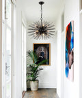 Black Sputnik Starburst Chandelier With 12 Lights 24 Inches Mid Century Firework Pendant Light Fixture in modern hallway.