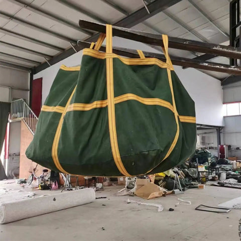 Rock Solid Heavy Duty Crane Lifting Bag Anti Tear Reusable Cargo Net hanging in a warehouse, showing thick nylon material and straps.