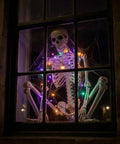 Life Size Skeleton Five Point Four Foot Poseable Full Body Halloween Prop with Movable Joints in window with lights