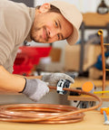 Person using Ratcheting Tubing Cutter 1/4 to 7/8 Inch 2 in 1 Close Quarters Pipe Cutter on a copper pipe in a workshop.