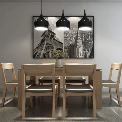 Dining room with wooden table and chairs, black pendant lights, and framed cityscape artwork on wall.