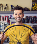 Man in yellow shirt holding a 26-inch bicycle wheel with a 36Pcs 14G Bicycle Spokes Kit 2mm Diameter 260mm Length for 26 Inch Rims