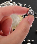580-Piece Stainless Steel Bearing Balls Kit 1.0mm Through 10.0mm Portable Precision Balls For Mechanical And Industrial Use, Wear-Resistant, Easy-Storage Assortment Built For DIYers And Pros In The Shop. hand holding a stainless steel bearing ball with assorted balls and coin