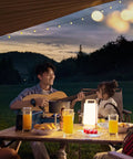 Camping scene with man playing guitar and a child, illuminated by Solar Camping Lantern With 6000mAh Rechargeable Battery Up To 80 Hours Of Light