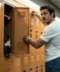 Person using beige locker, holds door handle in hallway, casual attire.