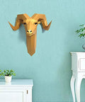Gold geometric ram head wall decor on light blue wall with potted plants and white furniture.