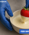 SAFESKIN blue nitrile disposable gloves, large, 2.0 mil, powder-free; gloved hand dipping strawberry into cream.