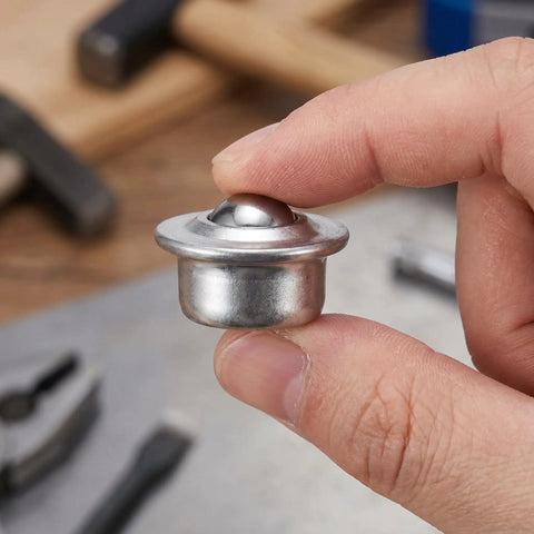 Close-up of a single unit from Six Pack Stainless Steel Ball Transfer Units With Omnidirectional Roller Bearings held between fingers.