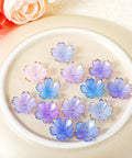100 Pcs Cherry Blossom Acrylic Flower Beads For Jewelry Making And Bracelet Charms, Pink And Blue Gradient With Gold Edge Petal Mini Spacer Beads, Super Cute Floral Beads Set For DIY Jewelry Projects displayed on a beige plate