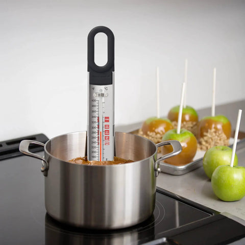 Curved Candy And Deep Fry Thermometer With Pro Grade Stainless Steel Paddle in pot with caramel apples in background