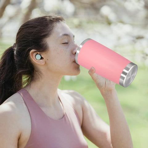 Woman enjoying drink from a pink insulated tumbler, highlighting the 20 Ounce Stainless Steel Tumbler With Secure Lid Pink Insulated Coffee Cup Durable Rustproof Bpa Free Lid Keeps Drinks Ice Cold All Damn Day Built Tough For Friday Night Vibes And Monday Morning Hustle.