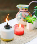 Adjustable Flame Glass Votive Table Top Torch For Outdoor Yard Patio And Deck, Refillable Flame Control, 6.75 Inch displayed on table.