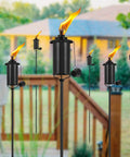Outdoor Metal Torch Set Of Six, 16 Oz Citronella Torches With 59 Inch Adjustable Height shown in a garden setting