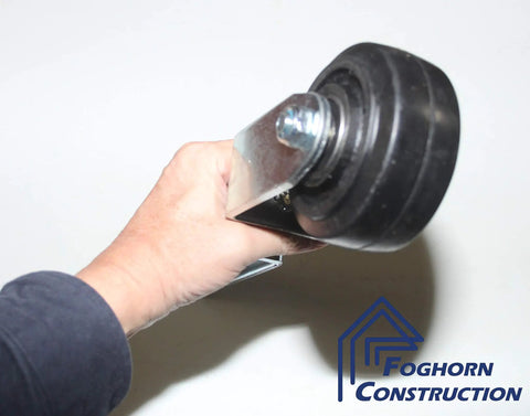 Person holding rugged heavy duty gate and door caster with spring loaded suspension, 4 inch fixed wheel, square shaft.