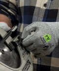Top Shelf ANSI A4 Cut Resistant Work Gloves With Smooth Polyurethane Grip And Durable DuraBlend Shell Built Tough For Grease Monkey Tasks Providing Rock Solid Level 5 Abrasion And Level 4 Puncture Protection In Large Fits Bulk Pack Of 24 Pairs, worn while handling a circular saw.