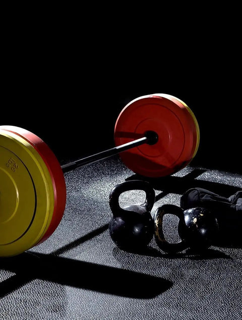 Barbell with red and yellow weight plates on gym floor, kettlebells beside it, heavy duty 2 inch barbell clamps quick release pair locking Olympic weight plate collars red and black easy weight swaps for powerlifting home gym fitness training clips