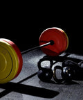 Barbell with red weight plates and yellow Heavy Duty 2 Inch Barbell Clamps Set Quick Release Locking Collars For Olympic Weight Plates.