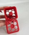 Label Dispenser Storage Box For Desk And Home Office, Space Saving Organizer Tray For Labels, Stickers, And Supplies, Lightweight, Durable, And Tidy Desktop Organizer For Efficient Desk Storage. Red plastic honeycomb label dispenser box shown open in hand