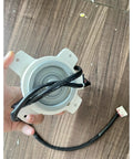 Person holding DC Brushless Air Conditioner Motor 25W 0010401701F replacement for variable frequency AC fans, showing connector.