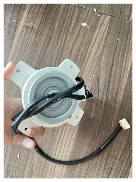 Person holding DC Brushless Air Conditioner Motor 25W 0010401701F replacement for variable frequency AC fans, showing connector.