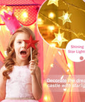 Girl with red star wand inside Princess Castle Tent For Girls With Star Lights Large Indoor Outdoor Playhouse Private Hideaway For Kids 55 Inch By 53 Inch Castle Style Toy Tent Fairy Tale Bedroom Play Space For Imaginary Adventures Totally Magical, surrounded by glowing star lights.