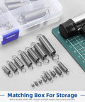96-piece stainless steel extension springs with double hooks in 15 sizes, arranged on a white work surface near a storage box.