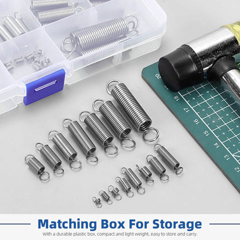 96-piece stainless steel extension springs with double hooks in 15 sizes, arranged on a white work surface near a storage box.