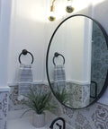 Brass Three Light Vanity Wall Fixture For A Modern Farmhouse Bathroom Vibe, 24 Inch Wide with exposed bulbs over oval mirror