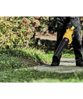 Person using 60V Max FlexVolt Cordless Handheld Leaf Blower 125 MPH Air Speed 600 CFM Airflow Tool on garden path