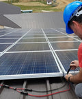 Installation of Plug And Play Solar Panel Extension Cable 20FT 14AWG Waterproof on rooftop solar array by technician in blue helmet.