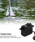 Beefy Metal Gear Sail Winch Servo Motor With Alloy Gears Analog Servo for Ship Rope Rewind next to a model sailboat on water