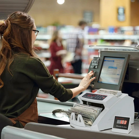 Cashier using Money Counter With Value Count And UV MG IR Counterfeit Detection in supermarket checkout.