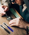 Watch enthusiast using Must Have Dual Function Watch Case Opener And Spring Pin Tool Set for repair on wooden desk