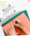 Badass Transparent Rolling Ruler And Drafting Kit For Slick Parallel Lines Precise Protractor Angles Smooth Arc Tracing Multi Function Layout Tool 2 Pack For Creators being used to trace on orange paper.