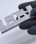Top Shelf HSS Planer Blades Set Of Eight Heavy Duty Hand Planer Replacement Knives Built Tough For The Woodworking Shop Boasts Crisp Cuts Every Single Time For Reliable 3 1 4 Inch Model Compatibility held in gloved hand.