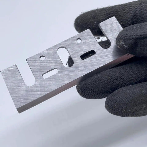 Top Shelf HSS Planer Blades Set Of Eight Heavy Duty Hand Planer Replacement Knives Built Tough For The Woodworking Shop Boasts Crisp Cuts Every Single Time For Reliable 3 1 4 Inch Model Compatibility held in gloved hand.